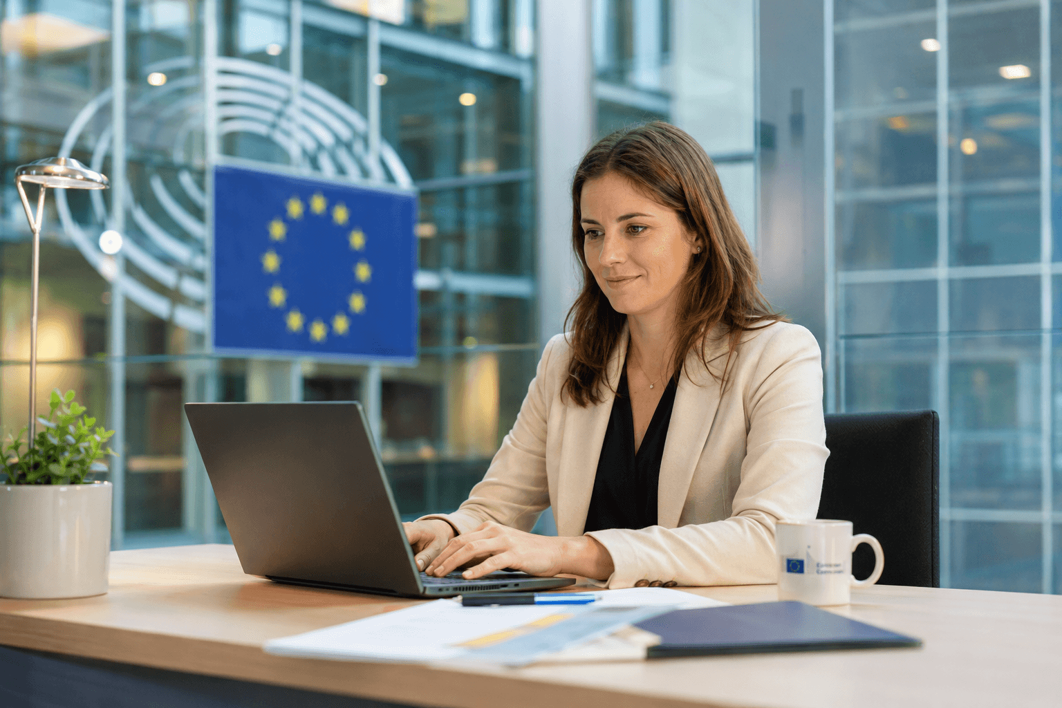 Professional working at a desk in a modern EU institution office with documents and a laptop